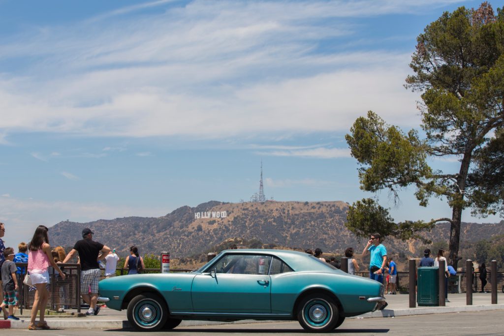Car with the Hollywood sign way in the background, we bet they're checking Hollywood's Most Haunted hot spots... you should too!